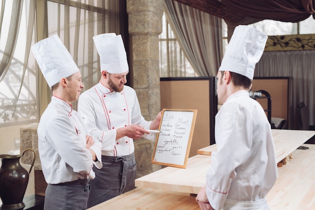 Küchenchef und seine Mitarbeiter in der Küche. Interaktion in der gewerblichen Küche.