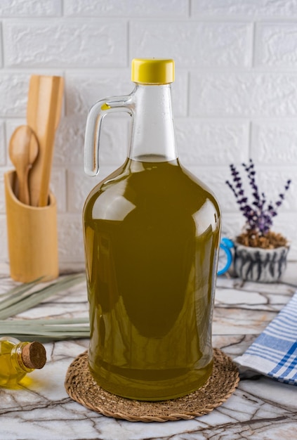 Foto küchenkonzept und ölgefüllte große glasflasche. olivenöl-ballonflasche auf marmorhintergrund.