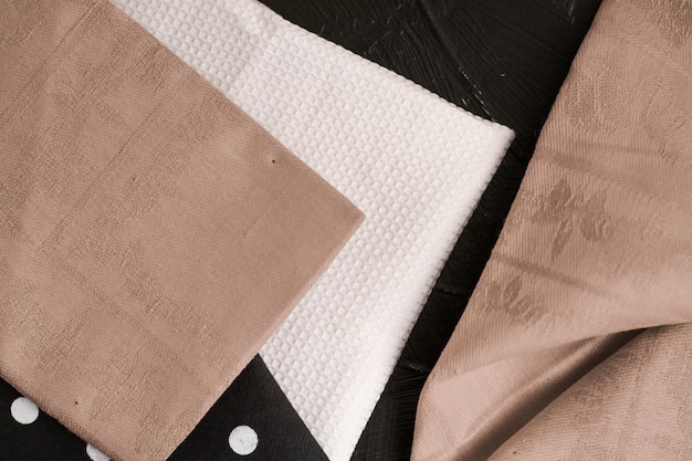 Küchentextilien auf schwarzem rustikalem Holzhintergrund Servietten- und Handtuchset gefaltete Stoffe als Food-Styling-Requisiten für die Innenarchitektur von Luxus-Wohnkulturmarken
