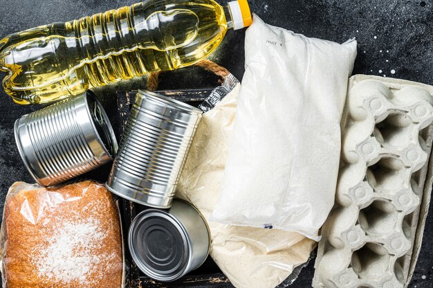 Foto küchentisch mit lebensmittelspenden, quarantäne-hilfekonzept. öl, konserven, nudeln, brot, zucker, ei.