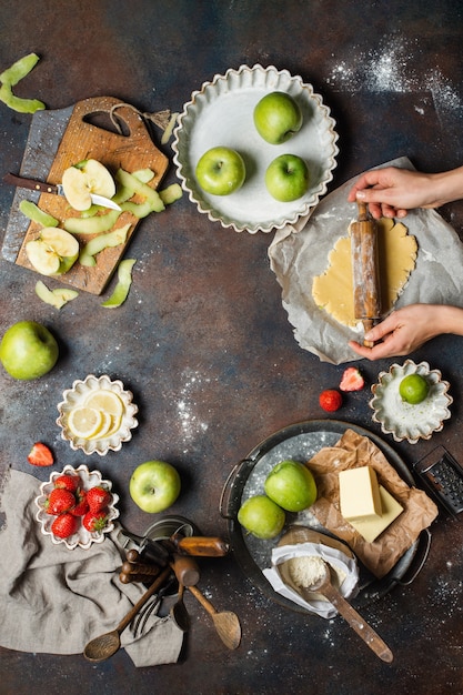 Küchentisch mit Äpfeln, Mehl, Butter, Erdbeeren und Zitrone