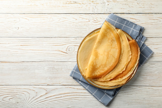 Küchentuch mit Platte der dünnen Pfannkuchen auf hölzernem Hintergrund