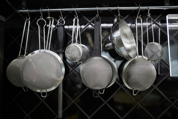 Küchenutensilien hängen an der Küchenwand Küchenutensilien aus Metall hängen an der Wand in der Küche