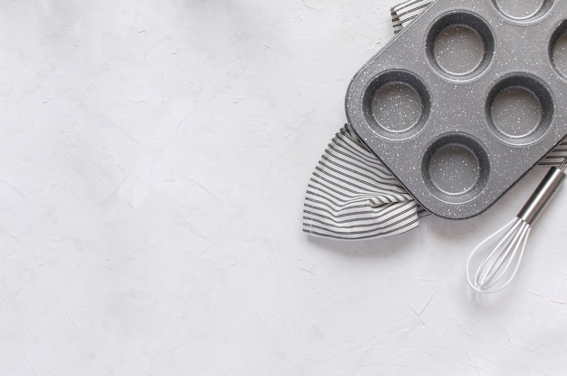 Küchenutensilien zum Backen - Cupcake Metallform Schneebesen auf zerknitterte gestreifte Serviette.