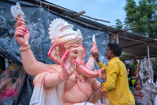 Künstler, der eine Statue herstellt und einem Idol des Hindu-Gottes Lord Ganesha in einem Artist39s-Workshop für das Ganesha-Festival den letzten Schliff gibt