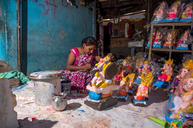 Künstler, der eine Statue herstellt und einem Idol des hinduistischen Gottes Lord Ganesha in einer Künstlerwerkstatt für das Ganesha-Fest den letzten Schliff gibt.