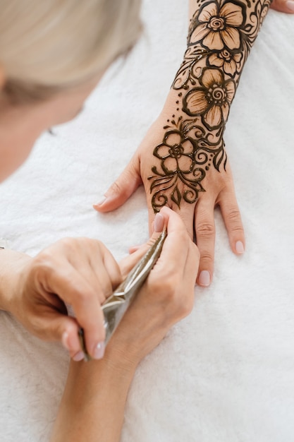 Künstler, der florales Henna-Tattoo auf Frauenhänden anwendet, entwerfen für Schönheit