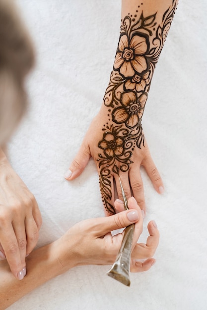 Künstler, der florales Henna-Tattoo auf Frauenhänden anwendet, entwerfen für Schönheit