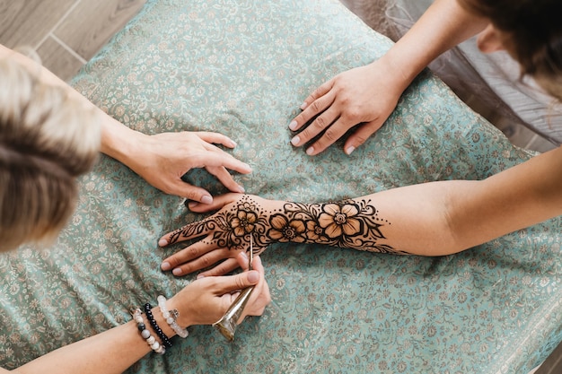Künstler, der florales Henna-Tattoo auf Frauenhänden anwendet, entwerfen für Schönheit