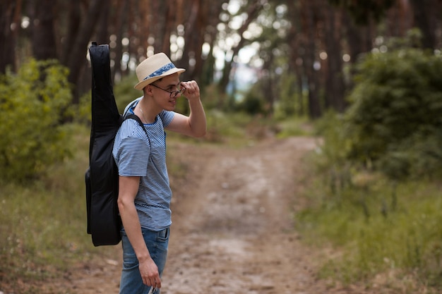 Künstler, der Gitarre im Wald spielt. Bardenwandern und Reisender Lifestyle