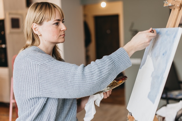 Künstler der jungen Frau, der ein Bild im Studio malt