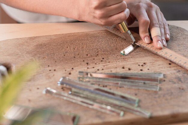 Künstler schneidet Buntglasplatten in kleine Mosaikquadrate. Nahaufnahme