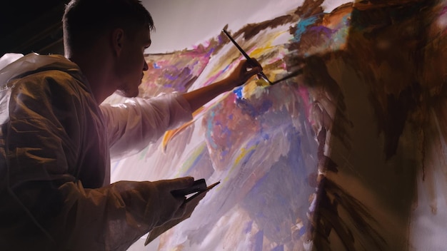 Künstlerdesigner zeichnet einen Adler an der Wand Handwerkerdekorateur malt Bild mit Acrylölfarbe und betrachtet Skizze im Telefon Dark Magic Cinematic
