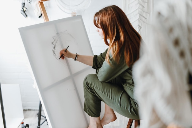 Foto künstlerin der jungen frau, die malerei im studio zeichnet