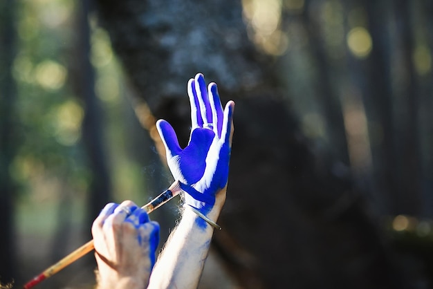 Foto künstlerin malt ihre hand blau im wald