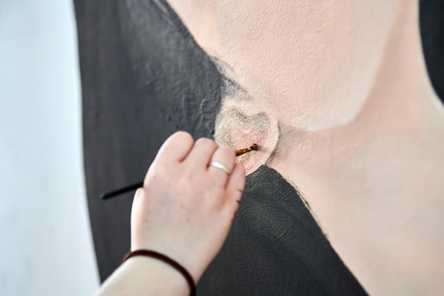 Künstlerin zeichnet mit Pinsel surreales Mädchenporträt auf weißer Leinwand bei der Kunstmalerei