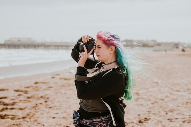 Künstlerische Frau, die ein Foto an einem Strand macht