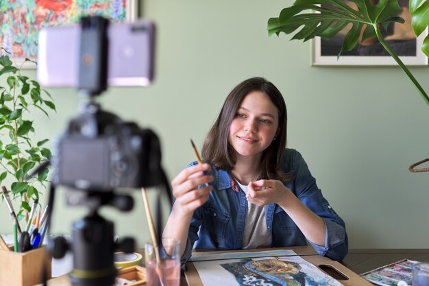 Künstlermädchen malt mit Aquarellen und macht Videos für ihren Kanalblog. Mädchen, das zeigt, was ihre Anhänger, Kinder und Jugendliche, anzieht und lehrt. Ausbildung, Bildung, Art Direction