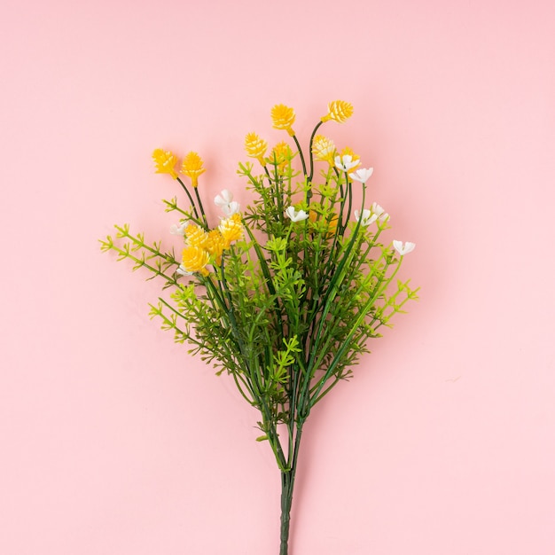 Künstliche Blume auf hellrosa Hintergrund.