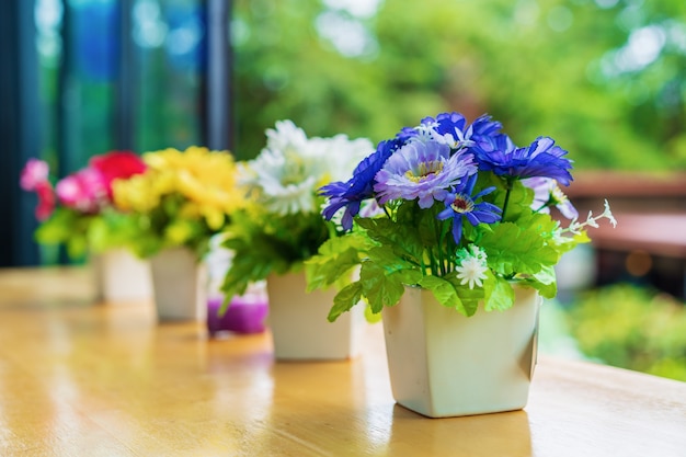 Künstliche Blume der bunten Dekoration im Topf auf Tabelle