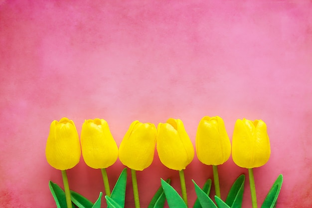 Künstliche gelbe Tulpen auf rosa Hintergrund für Naturdekoration und Frühjahrkonzept