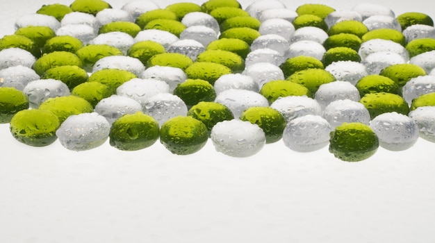 Künstliche runde Steine mit Wassertropfen von grüner und weißer Farbe. Nachahmung von Kieselsteinen