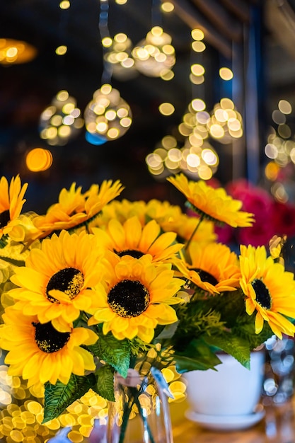 Künstliche Sonnenblume in Glasvase zur Dekoration für Weihnachtsdekoration Lichter in Form von auf Bokeh-Hintergrund Dekoration während Weihnachten und Neujahr.