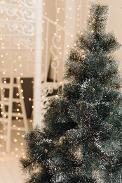 Künstlicher Weihnachtsbaum im hellen Innenraum des Hauses ohne Spielwaren. Baum mit künstlichen Zweigen zu schließen