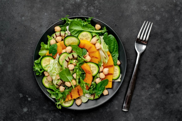 Kürbis, Avocado, Gurke, Kichererbsen, Salat auf einem Teller. Leckerer gesunder Salat