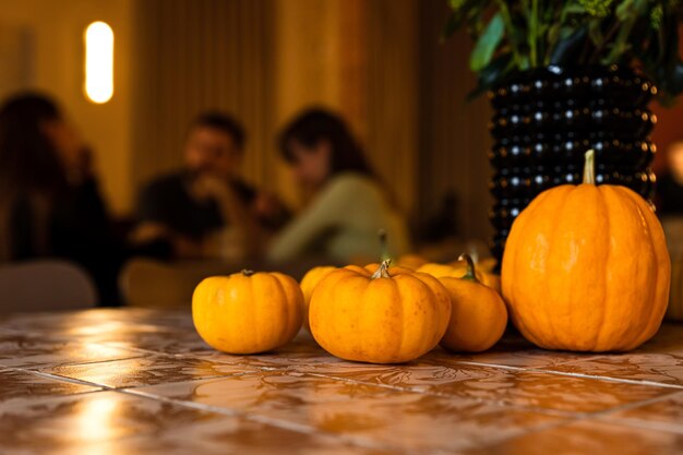 Kürbis Herbst Halloween-Dekoration auf dem Tisch Atmosphäre eines Cafés im Bokeh-Hintergrund Leute plaudern