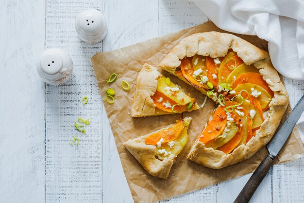 Kürbis-, Kartoffel-, Feta-Käse- und Lauch-Galette-Tortenplatte auf weißer hölzerner Tischoberfläche. Draufsicht.