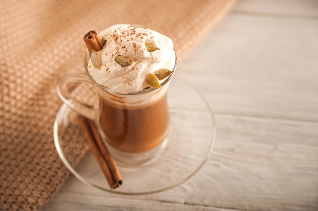 Kürbis Latte in einer transparenten Tasse Nahaufnahme und kopieren Raum Latte mit Creme Zimt Kürbisse Kürbiskerne auf einem weißen Teller Latte und Pullover