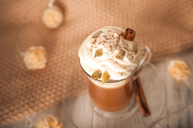 Kürbis Latte in einer transparenten Tasse Nahaufnahme und kopieren Raum Latte mit Creme Zimt Kürbisse Kürbiskerne auf einem weißen Teller Latte und Pullover