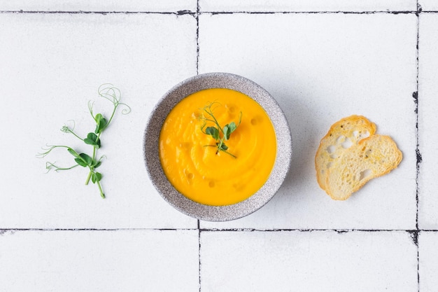 Kürbis- und Karottencremesuppe auf weißem Fliesenhintergrund mit Croutons Draufsicht hochwertiges Foto