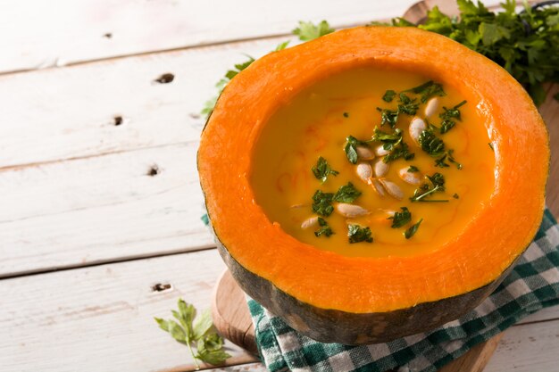 Kürbis- und Karottensuppe auf weißem Holztisch. Kopieren Sie Platz