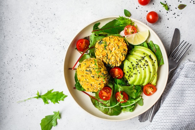 Foto kürbis- und quinoakoteletts des strengen vegetariers mit salat in einer weißen platte, draufsicht.