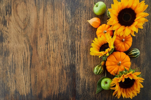 Kürbis und Sonnenblumen über altem hölzernem Hintergrund mit Kopienraum Herbsthintergrunddekoration