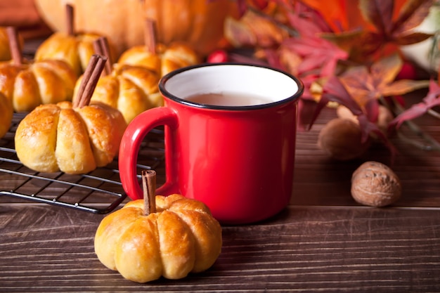 Kürbisbrötchen auf dem Backblech und einer Tasse Tee. Herbstkonzept. Warm und gemütlich.