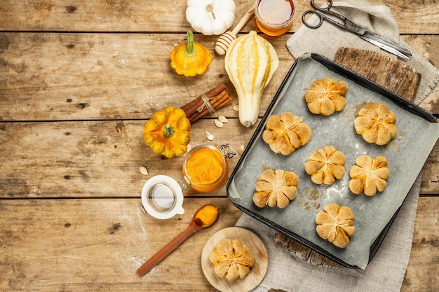 Kürbisbrötchen oder Kekse, traditionelle Herbstbackwaren. Saisonale Hausmannskost und Herbstdeko. Alte Holzbretter Hintergrund, Ansicht von oben