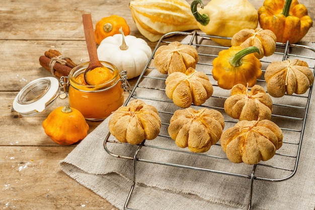 Kürbisbrötchen oder Kekse, traditionelle Herbstbackwaren. Saisonale Hausmannskost und Herbstdeko. Alte Holzbretter Hintergrund, Kopienraum