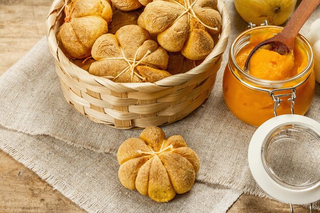 Kürbisbrötchen oder Kekse, traditionelle Herbstbackwaren. Saisonale Hausmannskost und Herbstdeko. Alte Holzbretter Hintergrund, Nahaufnahme