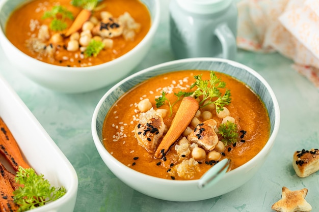 Kürbiscremesuppe Kürbis- und Karottenpüreesuppe mit Kichererbsen und Quinoa auf grünem Hintergrund Vegetarische Küche Vegane Rezepte