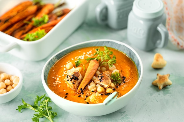 Kürbiscremesuppe Kürbis- und Karottenpüreesuppe mit Kichererbsen und Quinoa auf grünem Hintergrund Vegetarische Küche Vegane Rezepte