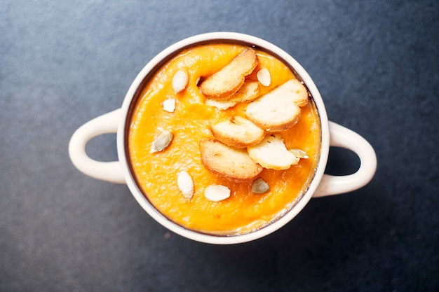 Kürbiscremesuppe mit croutons auf einem schwarzen tisch mit gewürzen. hochwertiges foto