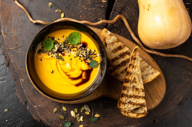 Kürbiscremesuppe mit gegrilltem Weißbrot. Kürbiskern, Balsamico, gebratene Quinoa. Diät veganes heiß gekochtes Gemüsegericht