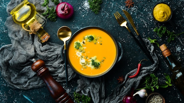 Kürbiscremesuppe mit Kürbiskernen in einer schwarzen Steinplatte Herbstmenü Diät Draufsicht Freier Platz für Text