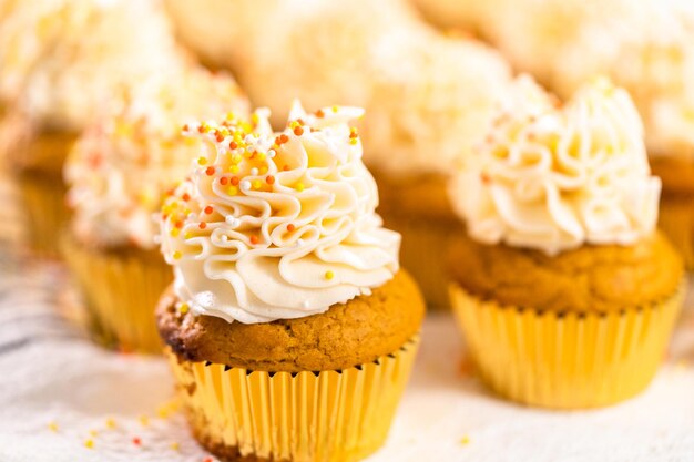 Kürbisgewürz-Cupcake mit italienischer Buttercreme und Streuseln dekorieren.