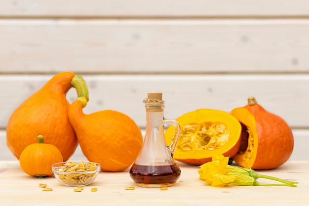 Kürbiskernöl im Glaskrug auf hölzernem Hintergrund. Ernte im Herbst. Erntedankfest.