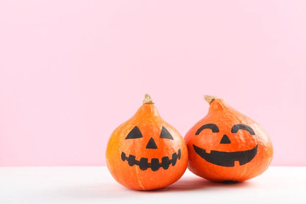 Kürbisse mit bemalten Gesichtern auf farbigem Hintergrund für Halloween