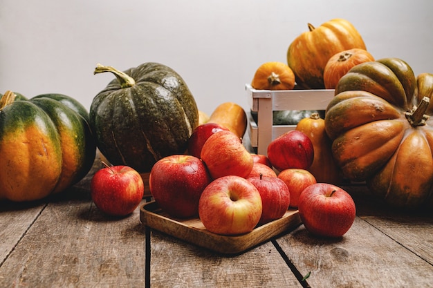 Kürbisse und rote Äpfel auf Grunge-Holztisch